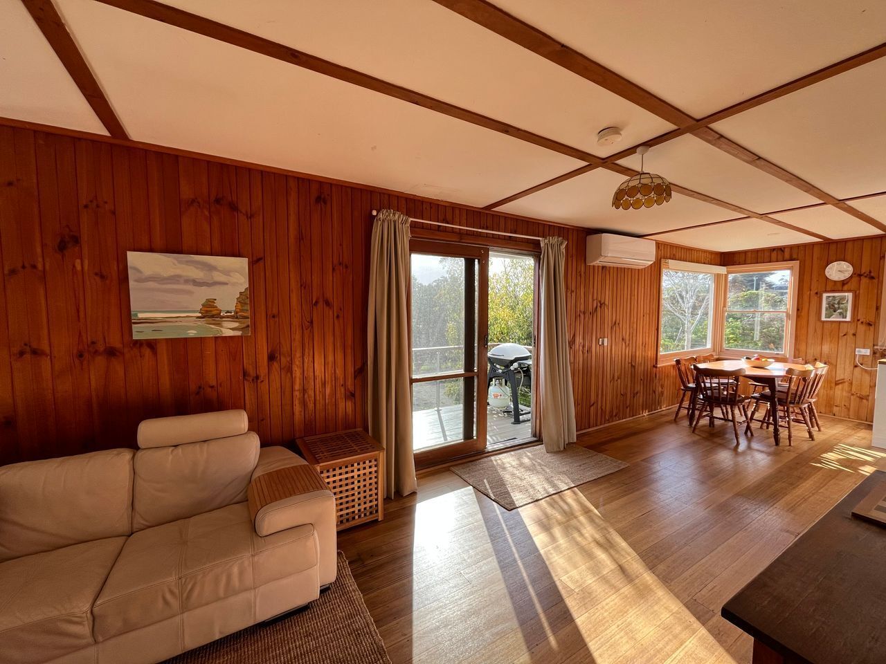 A wooden interior with a sofa, dining table, and chairs.