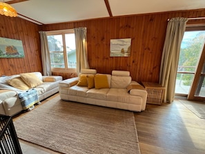 Ein gemütliches Wohnzimmer mit einem beigefarbenen Sofa, einem weißen Sessel und einem gemusterten Teppich.