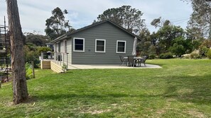 Enjoy outdoor dining or relaxation on the covered patio, surrounded by a well-maintained lawn and trees.