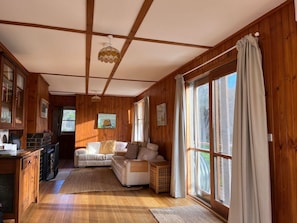 Ein gemütliches Blockhaus-Interieur mit Holzausstattung, einer Couch, einem Essbereich und großen Fenstern.