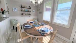 Een eetgedeelte met een ronde houten tafel, blauwe en witte borden en een kroonluchter.