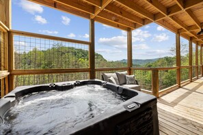 Relax in the hot tub surrounded by a serene forest view.