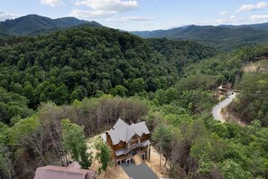 Escape to a serene forest retreat with a traditional cabin featuring a spacious porch and multiple windows.