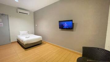 Una habitación de hotel con una cama, un televisor en la pared y una silla.