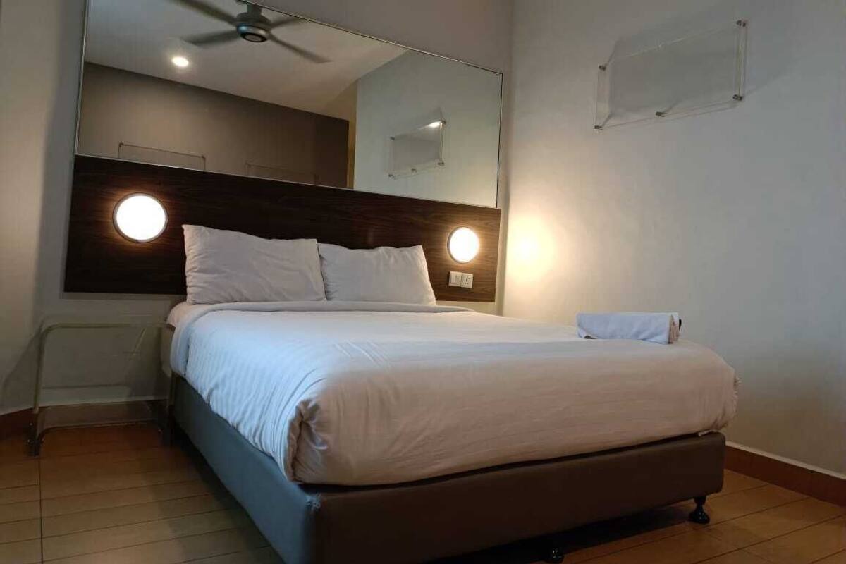 A neatly made bed with a headboard, a ceiling fan, and wall-mounted lights.