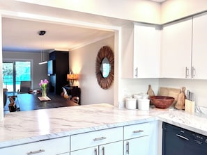 Una cocina moderna con armarios blancos, encimera de mármol y lavavajillas Bosch.