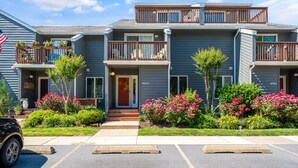 A two-story building with balconies, numbered units 1003 and 1004, and a parking area in front. - Spacious 3-Level Townhouse w/ 3 Community Pools, Tennis & Parking Pass for Rehoboth Beach (Rehoboth Beach)