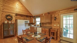 Une cuisine aménagée dans le style d’un chalet en bois, avec une table à manger, des chaises et un réfrigérateur.
