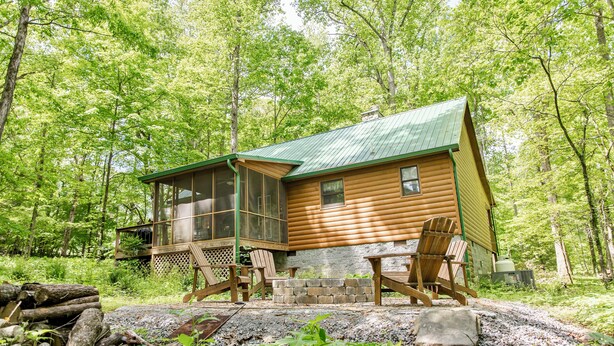 Une cabane dotée d’un porche en verre, d’une terrasse en bois et de meubles d’extérieur.