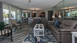 A spacious living area with a ceiling fan, a dining table, and a sofa.