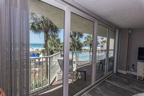 Un balcon avec vue sur une plage, une piscine et des palmiers.
