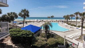 A pool area with a view of the beach and ocean.
