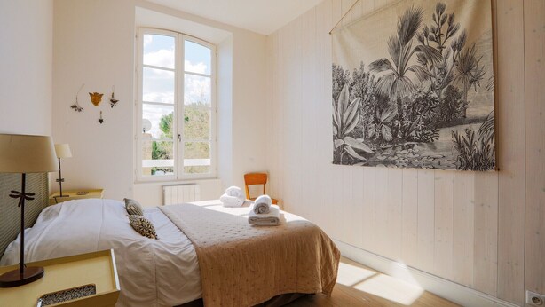 Un dormitorio con cama, ventana, tapiz en la pared y una silla.