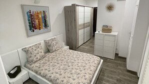 Un dormitorio moderno con una cama grande, un armario, una mesita de noche y una obra de arte en la pared.