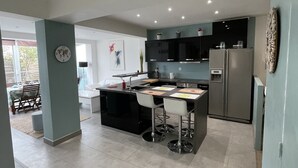 Una cocina moderna con una isla central, taburetes de bar y un refrigerador.