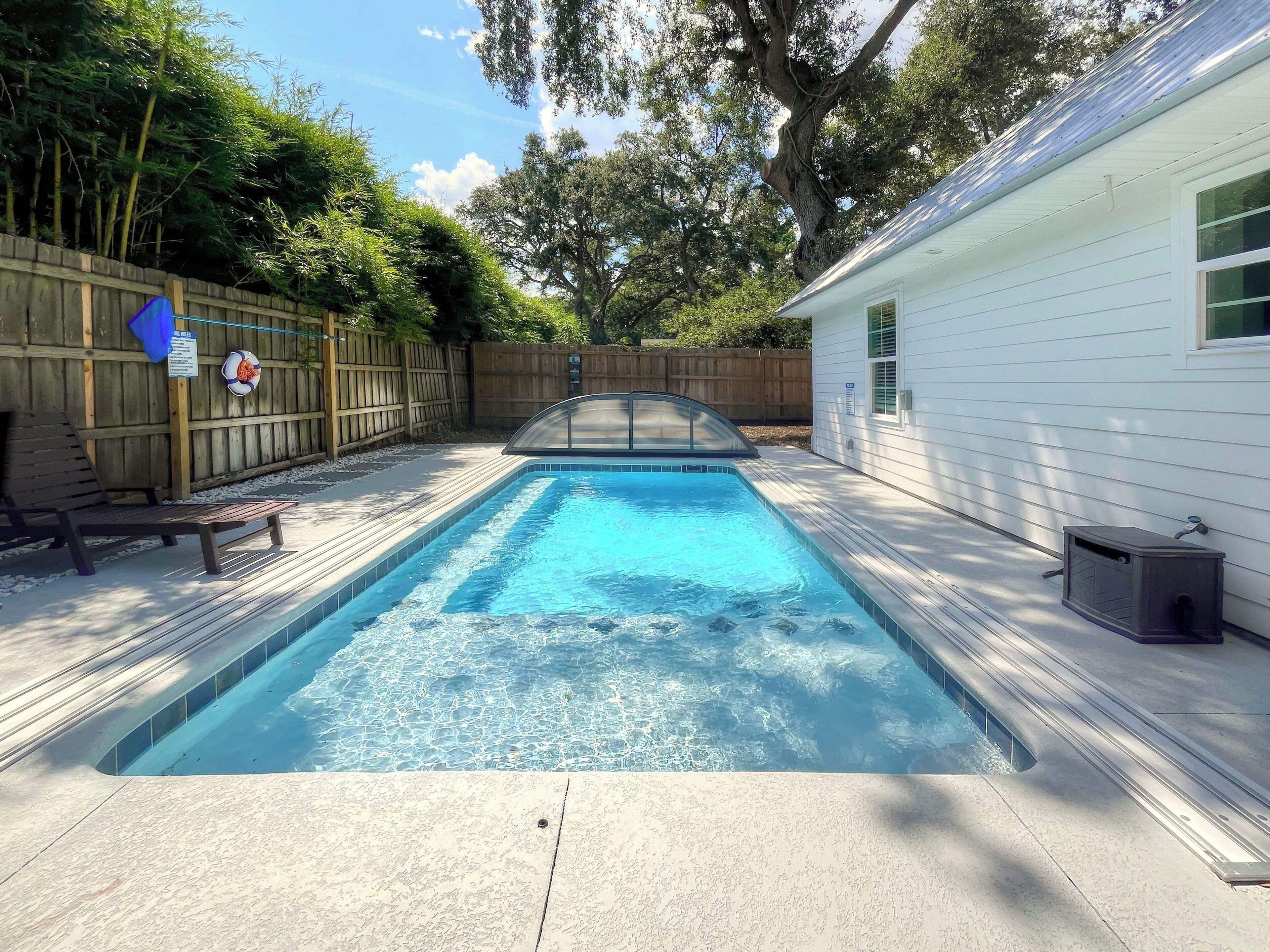 A rectangular swimming pool with a tiled edge, surrounded by a wooden deck.