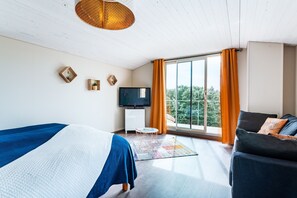 Relax in a stylish room with a comfortable sofa, flat-screen TV, and a large window offering a view of the outdoors.