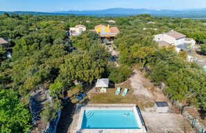 Surrounded by lush greenery, this property features a central pool and various buildings with unique architectural styles.