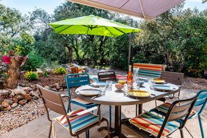 Enjoy al fresco dining in a serene garden setting, surrounded by lush greenery and comfortable seating.