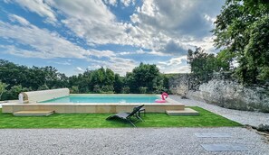 A swimming pool with a stone wall and a grassy area with a lounge chair. - Air-conditioned villa with pool & garden - Saint-Restitut (Saint-Restitut)