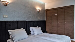 Una camera da letto con un letto grande, una testiera scura, due applique e un armadio in legno.