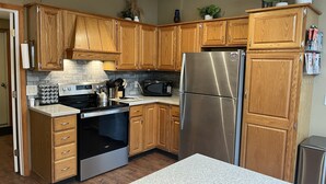 A modern kitchen with wooden cabinets, stainless steel appliances, and a granite countertop. - Riverhouse NEW renovation, riverfront, game rm, fishing, swimming, paddle sports (Milford)