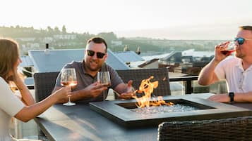 A terrace with a fire feature, outdoor seating, and a view of the city.