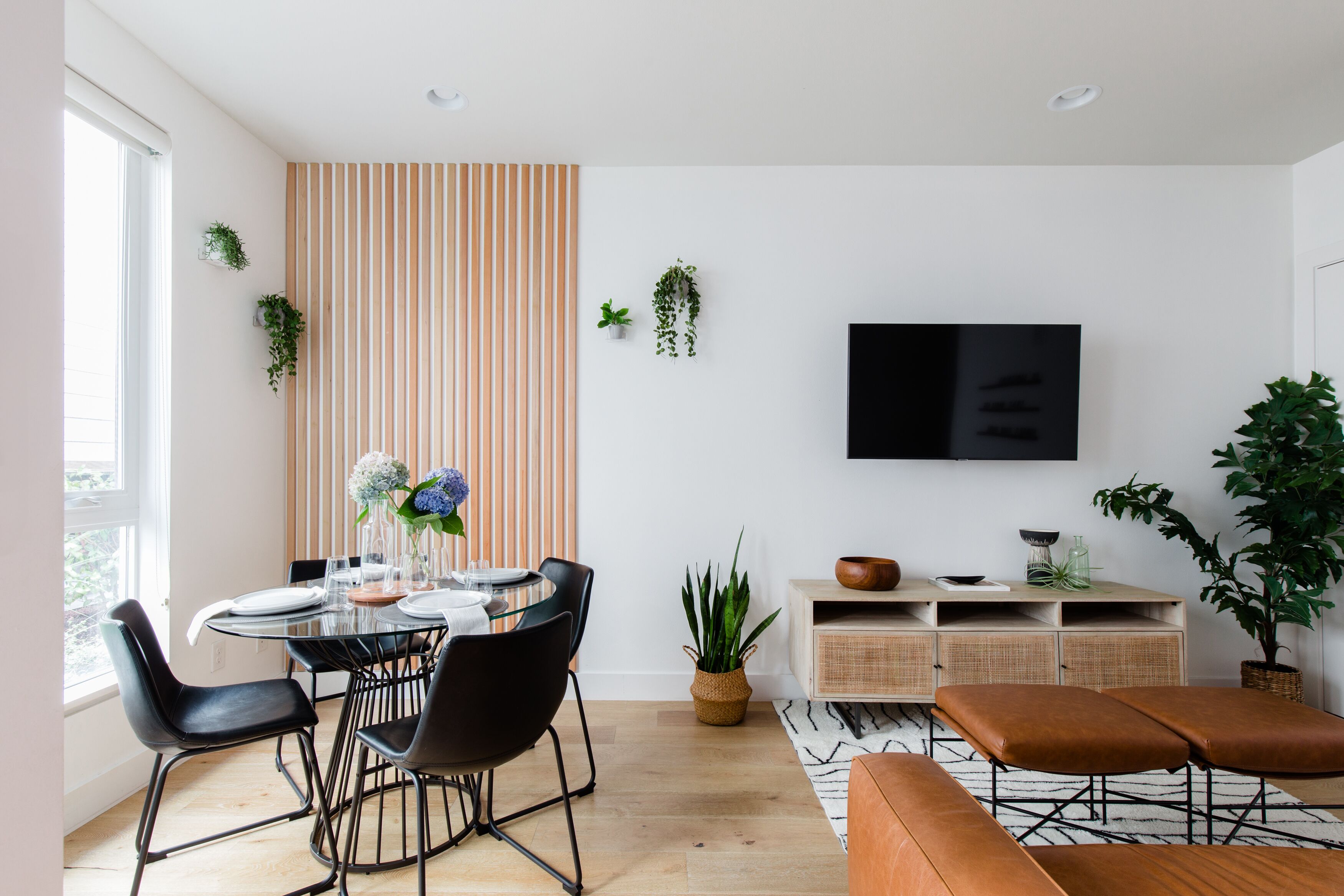 A modern dining area with a round glass table, black chairs, and a striped wall.