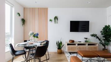 A modern dining area with a round glass table, black chairs, and a striped wall.
