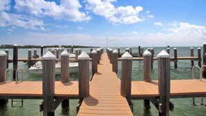 A wooden pier leading to a marina with boats docked, surrounded by calm water and a clear sky. - Changes in Latitude (MARATHON)