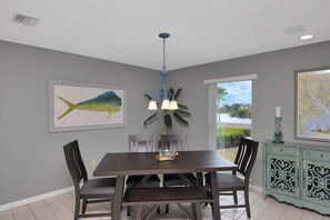 A dining area with a wooden table and chairs, a chandelier, and framed artwork on the walls. - Changes in Latitude (MARATHON)