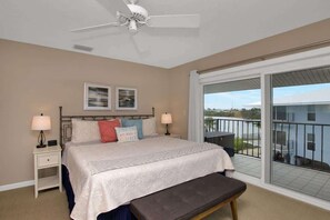 A bedroom with a large bed, two bedside tables, a ceiling fan, and a balcony with a view. - Changes in Latitude (MARATHON)