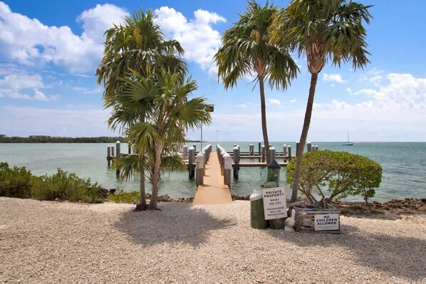A private property with a dock leading to a pier, a sign prohibiting children, and a clear view of the water.