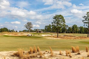 Un parcours de golf avec des bunkers de sable, un club-house et des arbres.