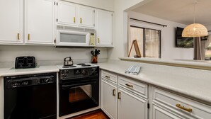 Een keuken met witte kasten, een magnetron, een broodrooster en een oven.