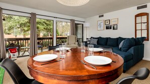 Een eetgedeelte met een ronde houten tafel voor vier personen, een bank en uitzicht op het landschap.