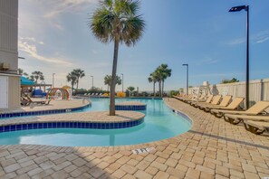 Relax by the pool surrounded by palm trees and lounge chairs on a tiled deck.