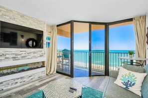 Un salon moderne doté d’une grande porte-fenêtre coulissante donnant sur un balcon avec vue sur la plage.