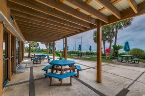 Guests can dine al fresco at this communal patio area, shaded by a pergola and surrounded by lush greenery.