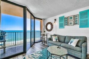 Relax in this ocean-view living area with a sofa, coffee table, and nautical artwork.