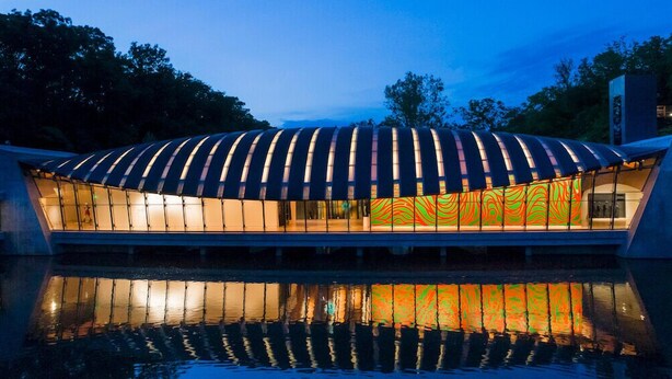 A modern building with a curved roof and large glass windows reflecting the sky. - Double Down: Spacious Lakefront Retreat with Stunning Views & Hot Tub (Bella Vista)