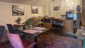 A dining area with a table set for four, a coffee machine, and a bookshelf. - Villa Monceau (Ottignies-Louvain-la-Neuve)
