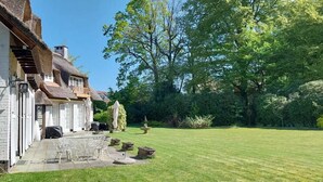 A house with a thatched roof, a paved patio with outdoor furniture, and a well-maintained lawn. - Villa Monceau (Ottignies-Louvain-la-Neuve)