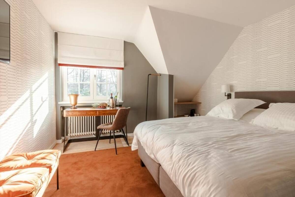 A bedroom with a bed, a desk, and a chair.