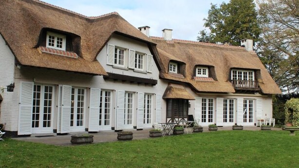 A traditional building with a thatched roof, white exterior walls, and multiple windows with shutters. - Villa Monceau (Ottignies-Louvain-la-Neuve)