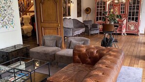 A living room with a brown leather sofa, a glass coffee table, and a red and white cabinet. - Villa Monceau (Ottignies-Louvain-la-Neuve)