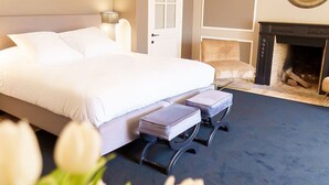 A bedroom with a bed, bedside tables, a fireplace, and a view of the outdoors. - Villa Monceau (Ottignies-Louvain-la-Neuve)