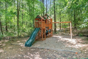 Children can play on the slide and climbing wall in this forest playground.