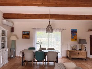 Un coin repas avec un plafond en bois, une table entourée de chaises, un vase rempli de fleurs et un tableau accroché au mur.