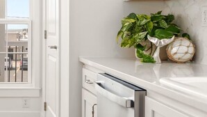 Una cocina moderna con armarios blancos, lavavajillas y una planta en maceta.